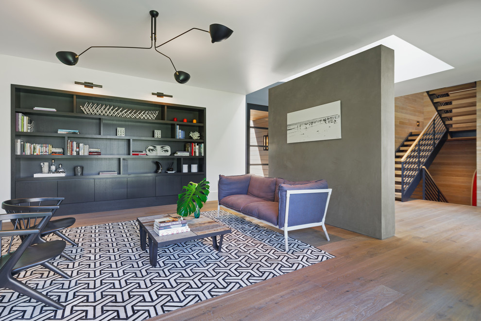 This is an example of a contemporary open plan living room in New York with white walls and medium hardwood flooring.