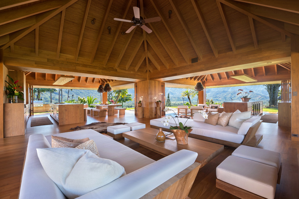 Immagine di un soggiorno tropicale con pavimento in legno massello medio e pavimento marrone