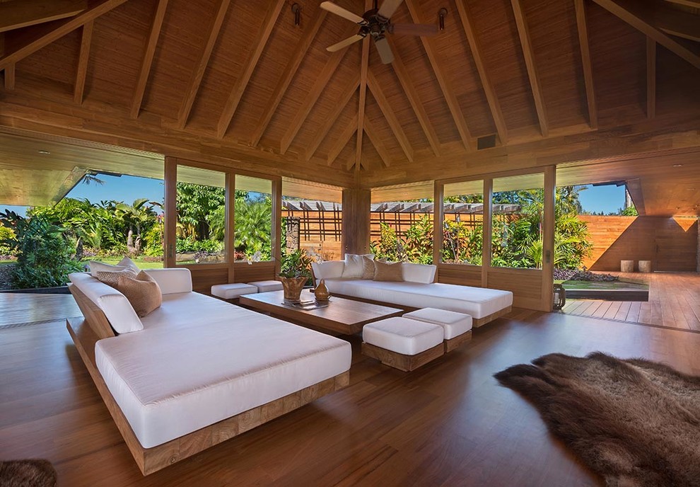 Immagine di un soggiorno tropicale aperto con pavimento in legno massello medio e nessun camino