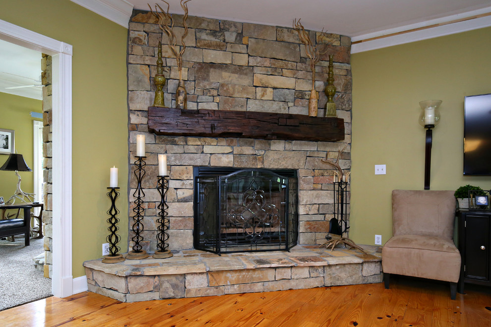 ルイビルにある高級なラスティックスタイルのおしゃれなリビング (緑の壁、淡色無垢フローリング、両方向型暖炉、石材の暖炉まわり、壁掛け型テレビ) の写真
