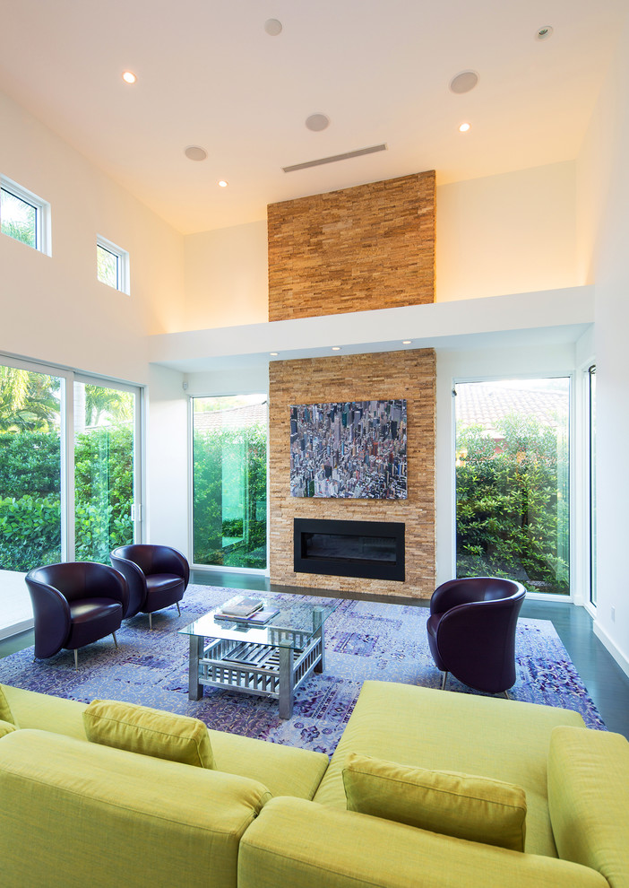 This is an example of a modern living room in Miami with a ribbon fireplace and a stone fireplace surround.