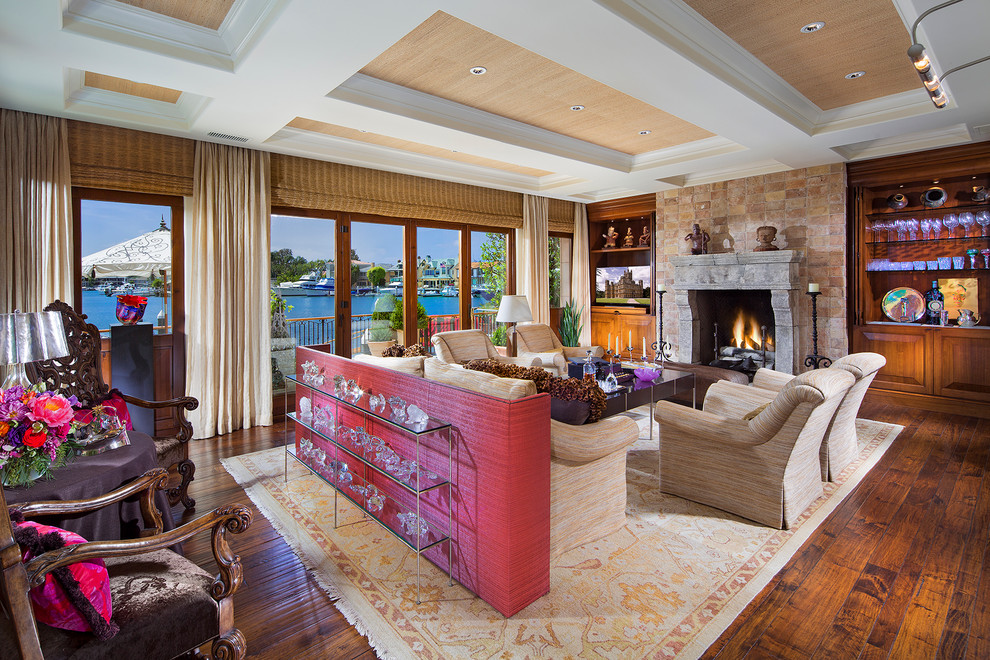 Inspiration for a large mediterranean formal open plan living room in Orange County with beige walls, medium hardwood flooring, a standard fireplace, a stone fireplace surround and a concealed tv.