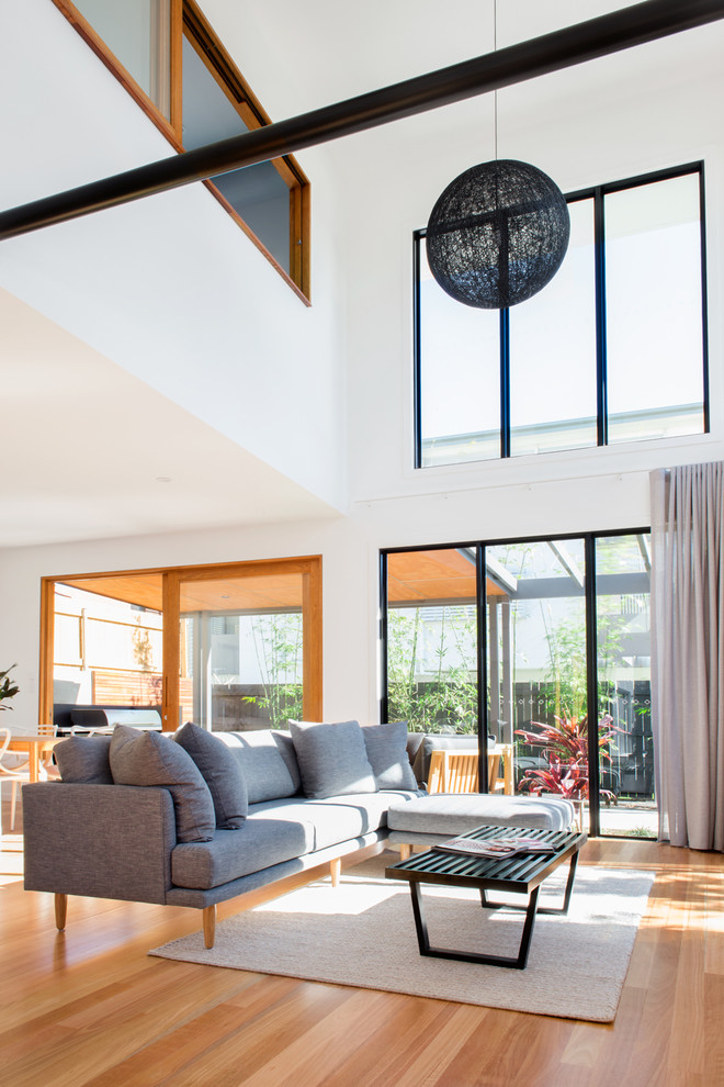 Immagine di un soggiorno design di medie dimensioni e aperto con pavimento in legno massello medio e pareti bianche