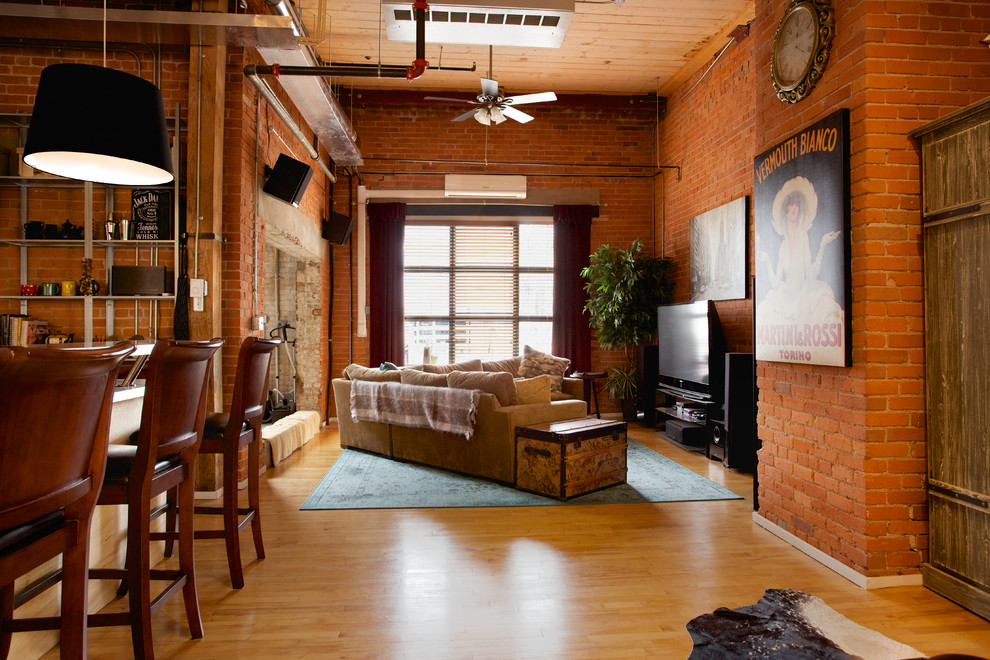На фото: открытая гостиная комната в стиле лофт с красными стенами, паркетным полом среднего тона и отдельно стоящим телевизором с