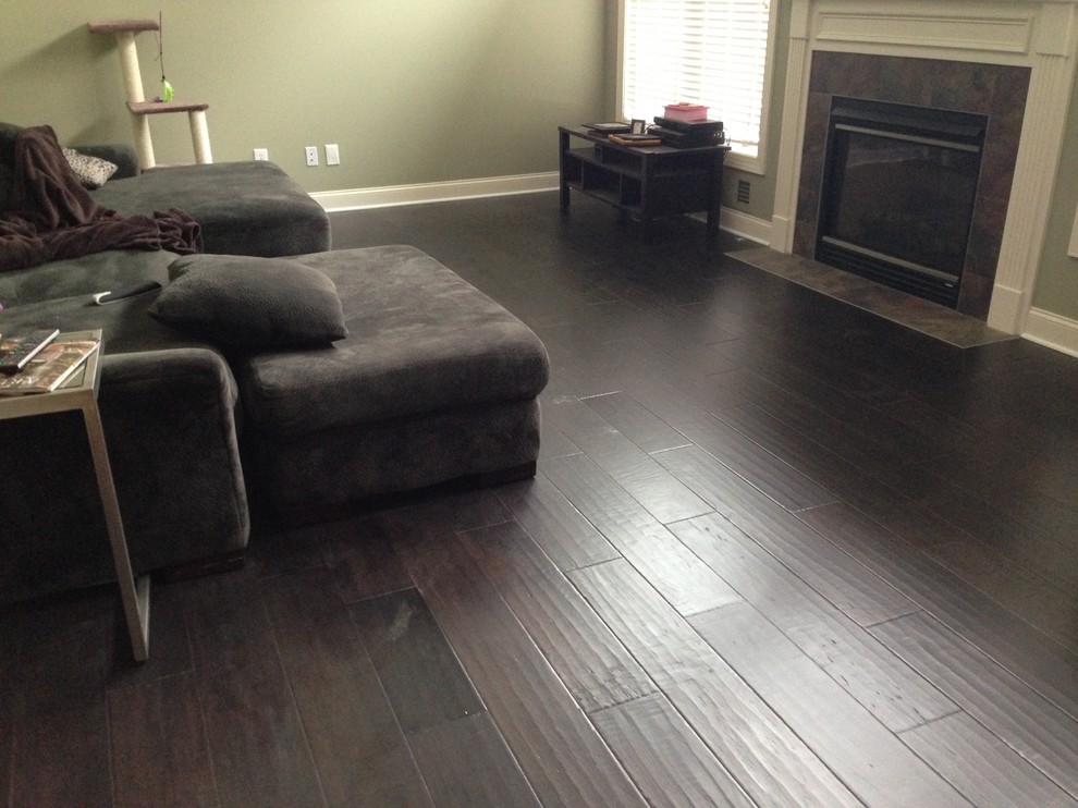 Photo of a medium sized enclosed living room in New York with green walls, dark hardwood flooring, a standard fireplace, a tiled fireplace surround and no tv.