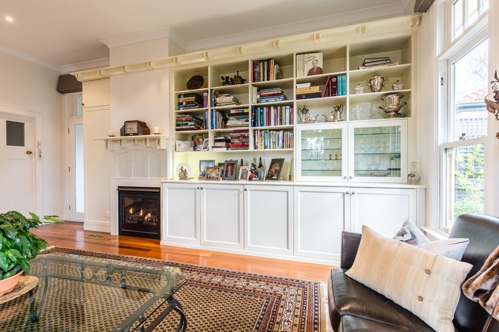 Großes Klassisches Wohnzimmer mit verstecktem TV, weißer Wandfarbe, braunem Holzboden, Kamin und Kaminumrandung aus Holz in Melbourne