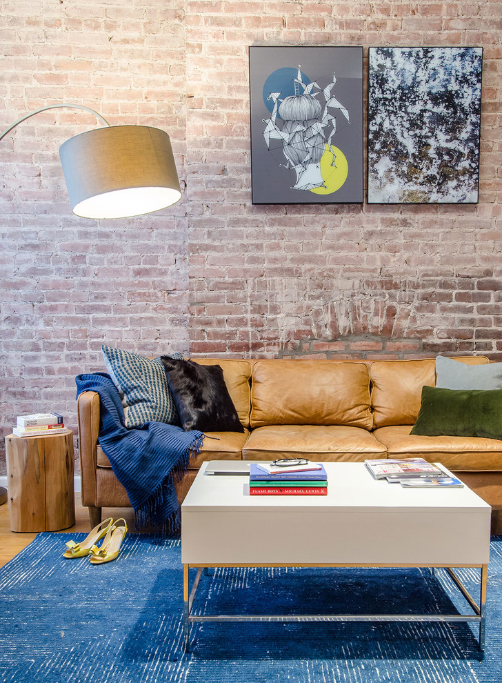 Living room - mid-sized industrial enclosed medium tone wood floor and brick wall living room idea in New York with red walls, no fireplace and no tv