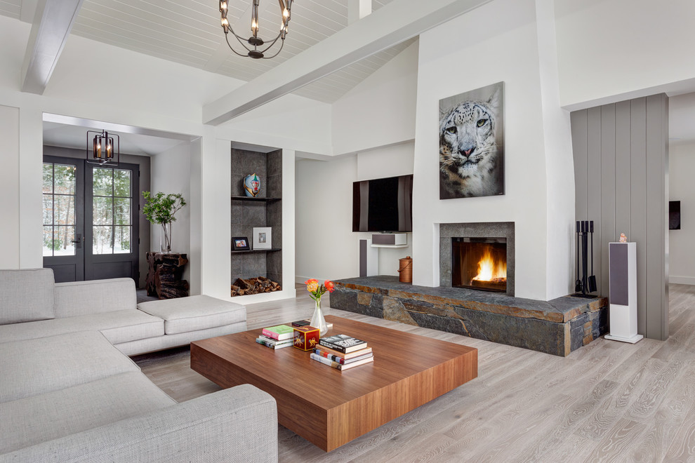 Medium sized contemporary open plan living room in Bridgeport with white walls, light hardwood flooring, a standard fireplace, a stone fireplace surround, a wall mounted tv and grey floors.