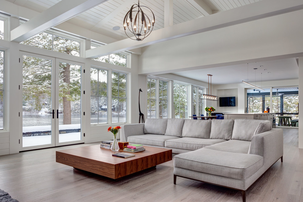This is an example of a medium sized contemporary open plan living room in Bridgeport with white walls, light hardwood flooring, a wall mounted tv and grey floors.