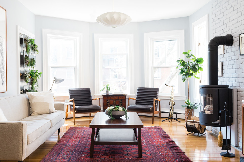 Skandinavisches Wohnzimmer mit weißer Wandfarbe, hellem Holzboden, Kaminofen und beigem Boden in Boston