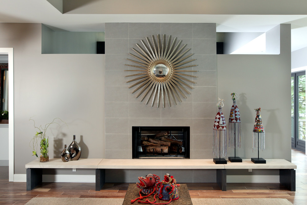 グランドラピッズにある広いコンテンポラリースタイルのおしゃれなLDK (グレーの壁、無垢フローリング、標準型暖炉、石材の暖炉まわり) の写真