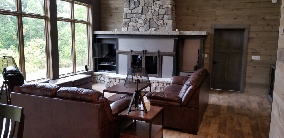This is an example of a rustic open plan living room in Grand Rapids with grey walls, vinyl flooring, a standard fireplace, a metal fireplace surround and brown floors.
