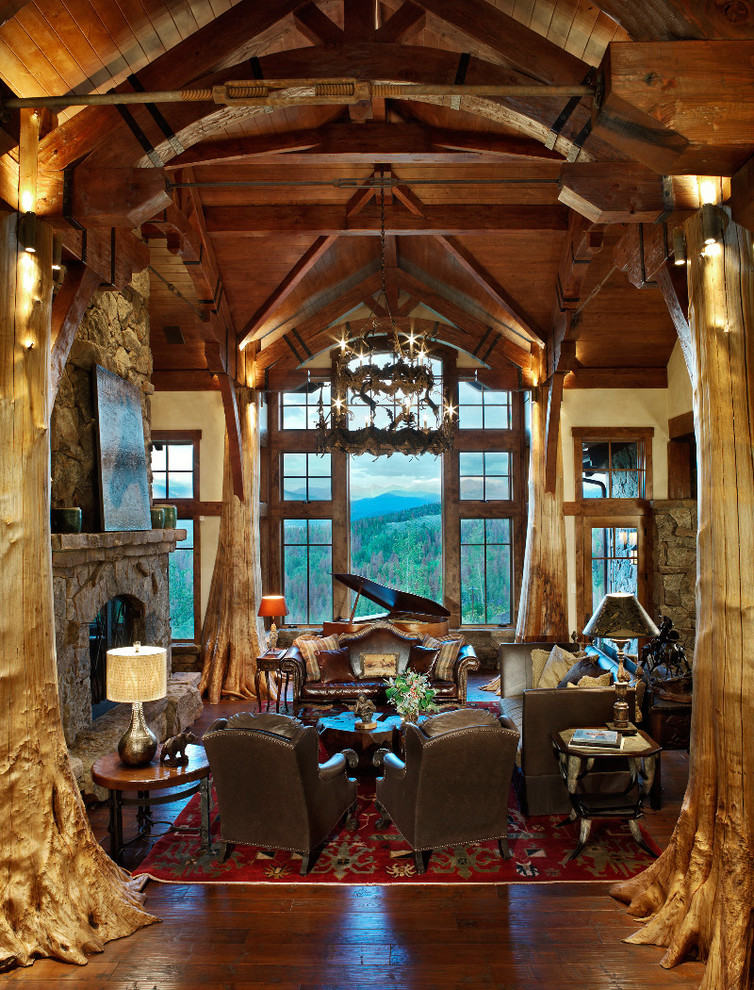 На фото: гостиная комната в стиле рустика с фасадом камина из камня и ковром на полу