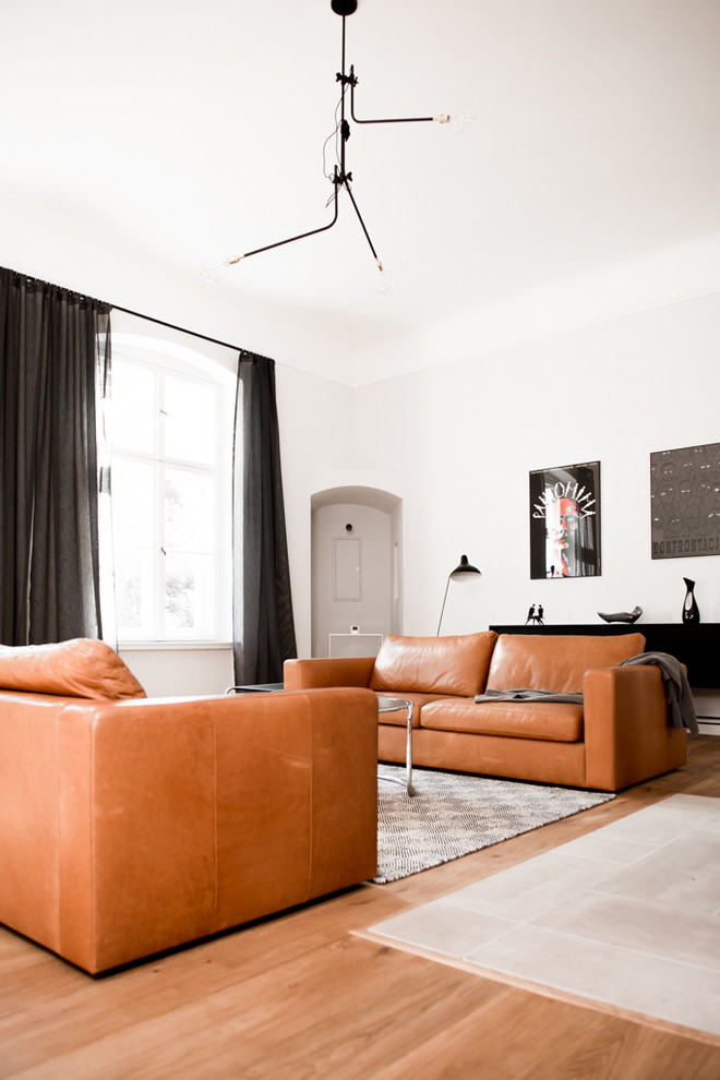 Mittelgroßes, Abgetrenntes Modernes Wohnzimmer mit weißer Wandfarbe, hellem Holzboden, Kamin, Kaminumrandung aus Stein und TV-Wand in Berlin