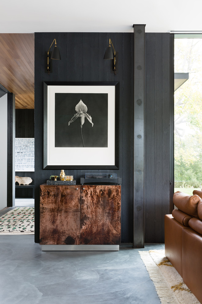 Стильный дизайн: гостиная комната в современном стиле с черными стенами, бетонным полом и серым полом - последний тренд