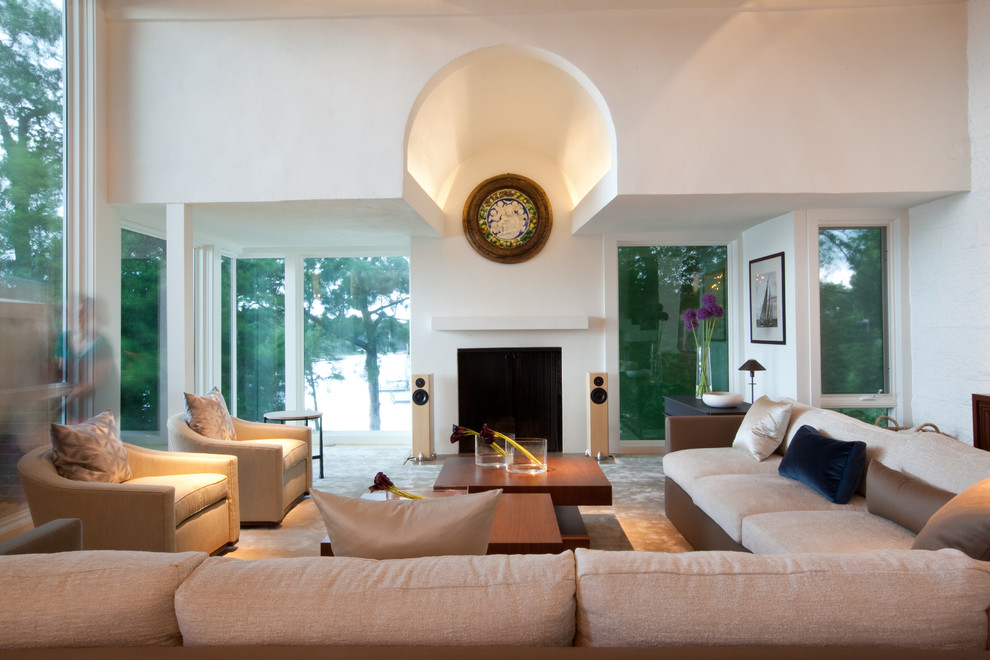Foto di un ampio soggiorno design aperto con pareti bianche, parquet chiaro, camino classico e cornice del camino in intonaco