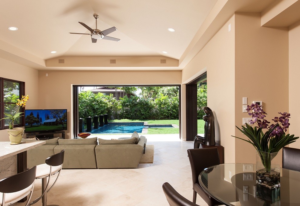 Inspiration för ett mellanstort tropiskt allrum med öppen planlösning, med beige väggar, kalkstensgolv och en fristående TV