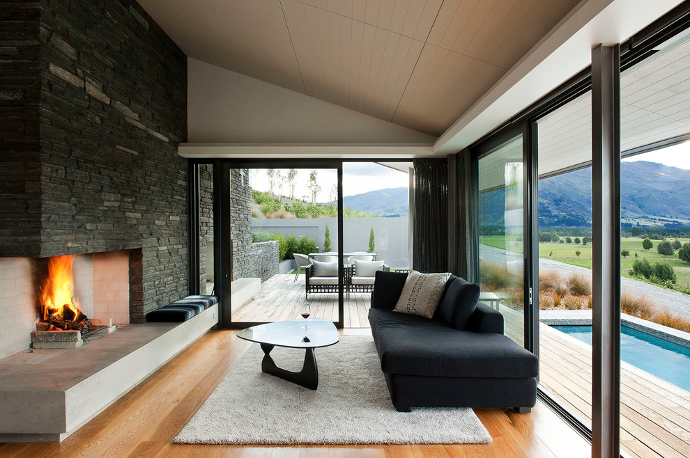 Modernes Wohnzimmer mit weißer Wandfarbe, braunem Holzboden, Kamin und Kaminumrandung aus Stein in Christchurch