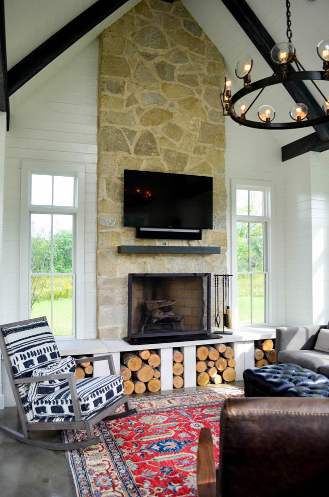 Cette photo montre un salon nature avec une cheminée standard, un manteau de cheminée en pierre, sol en béton ciré et un sol gris.