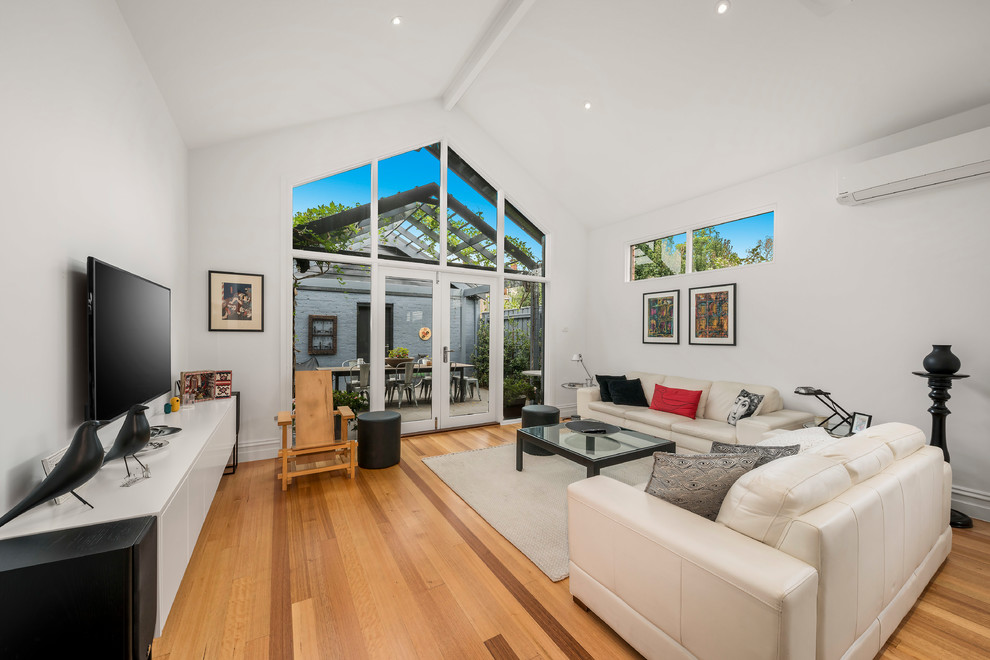 Repräsentatives, Abgetrenntes Modernes Wohnzimmer mit weißer Wandfarbe, braunem Holzboden, TV-Wand und braunem Boden in Melbourne