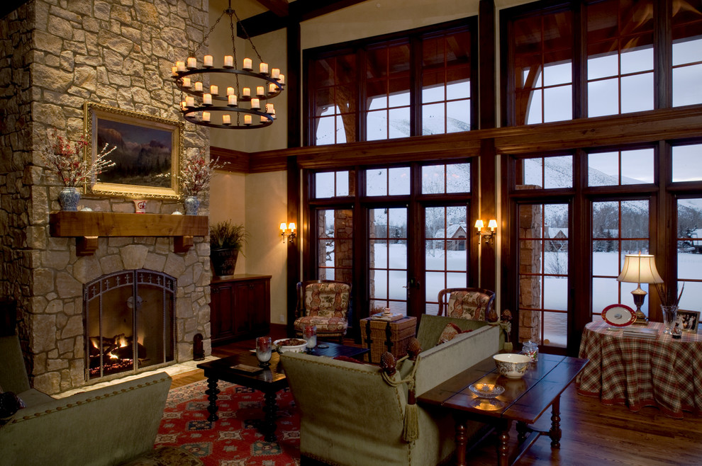 Idée de décoration pour un grand salon tradition ouvert avec un mur beige, un sol en bois brun, une cheminée standard, un manteau de cheminée en pierre et un téléviseur dissimulé.