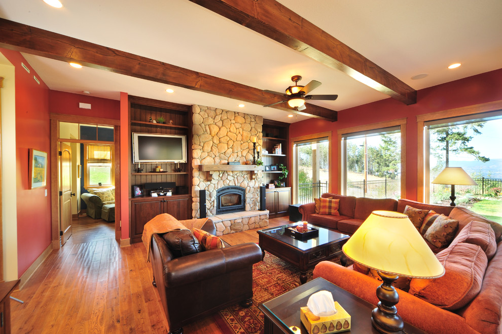 Idee per un grande soggiorno stile americano aperto con pareti rosse, pavimento in legno massello medio, camino classico e cornice del camino in pietra