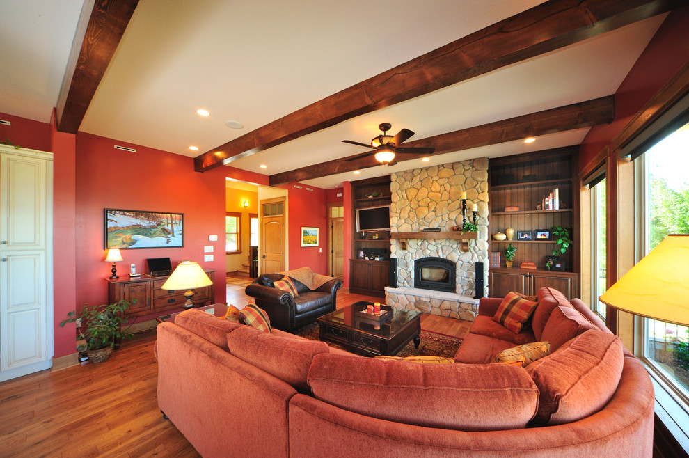 Пример оригинального дизайна: большая открытая гостиная комната в стиле кантри с красными стенами, паркетным полом среднего тона, стандартным камином и фасадом камина из камня