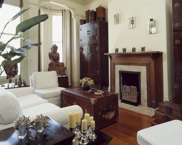 Modelo de salón cerrado bohemio pequeño sin televisor con paredes blancas, suelo de madera en tonos medios, todas las chimeneas y marco de chimenea de piedra
