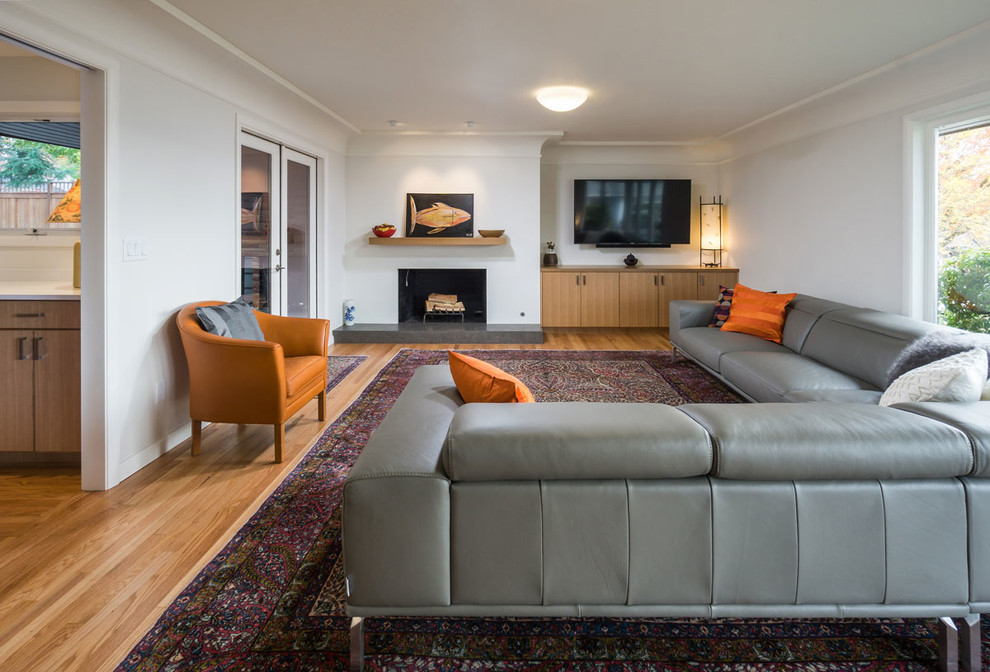 Свежая идея для дизайна: большая изолированная гостиная комната в современном стиле с серыми стенами, светлым паркетным полом, стандартным камином, фасадом камина из штукатурки, телевизором на стене и коричневым полом - отличное фото интерьера