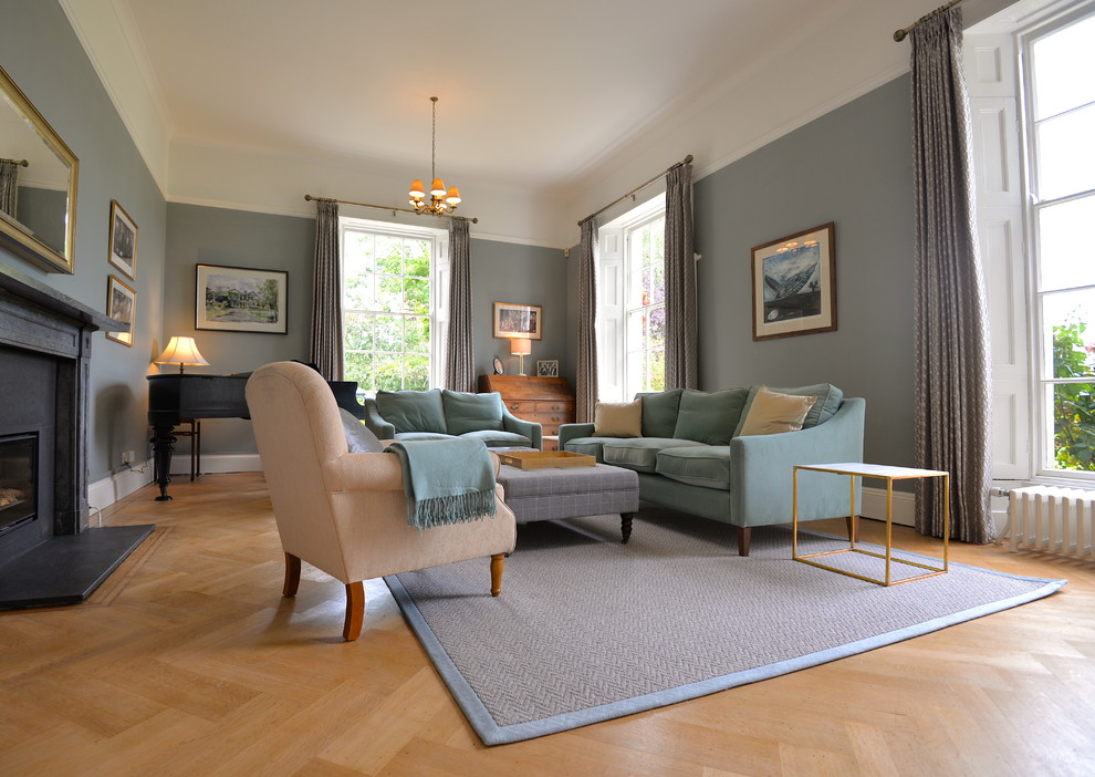 Klassisk inredning av ett mellanstort separat vardagsrum, med ett finrum, blå väggar, ljust trägolv, en öppen vedspis, en spiselkrans i sten, en dold TV och brunt golv