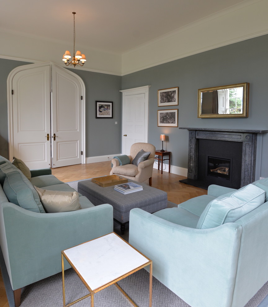 Inspiration for a medium sized traditional formal enclosed living room in Cambridgeshire with blue walls, light hardwood flooring, a wood burning stove, a stone fireplace surround, a concealed tv and brown floors.