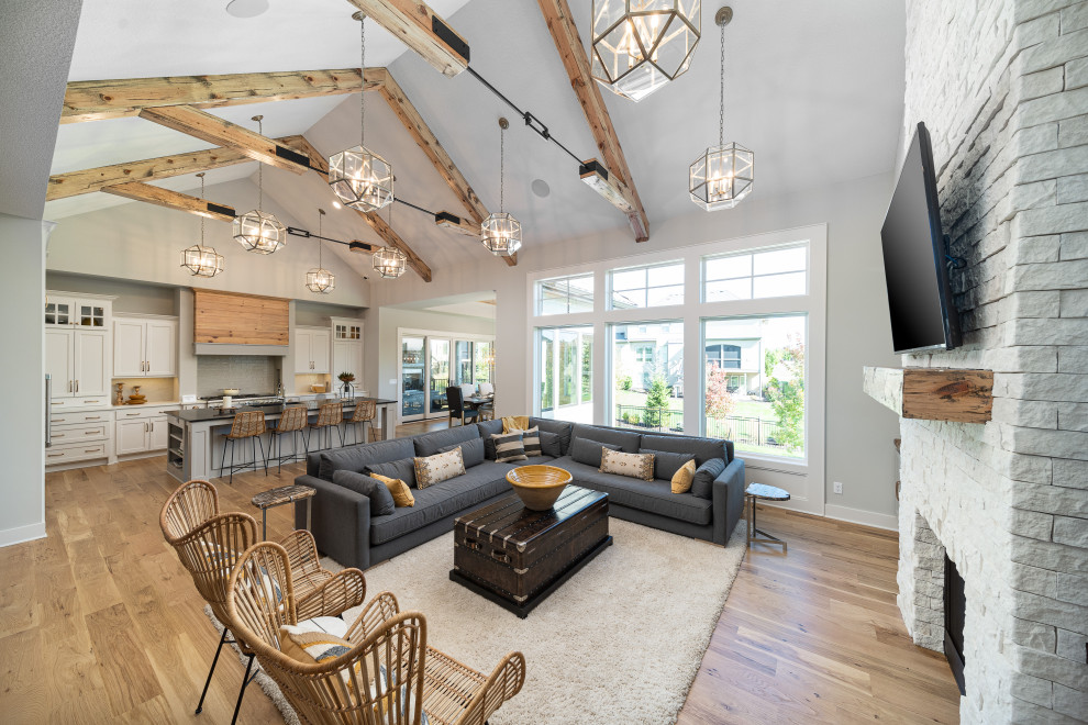 Farmhouse open plan living room in Kansas City with grey walls, light hardwood flooring, a standard fireplace, a brick fireplace surround, brown floors, exposed beams and a vaulted ceiling.