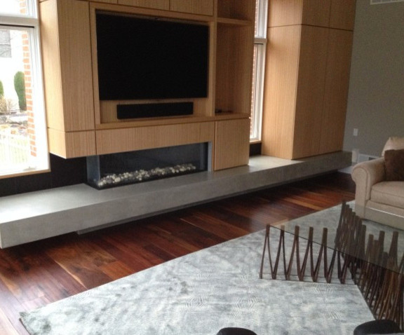 Cette image montre un grand salon design fermé avec un mur beige, une cheminée ribbon, un manteau de cheminée en bois, un téléviseur encastré, un sol marron et parquet foncé.