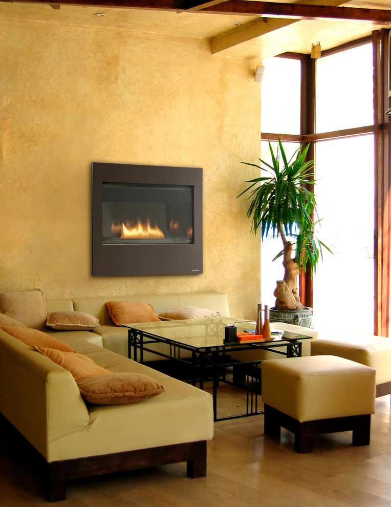 Esempio di un piccolo soggiorno minimal con pareti gialle, parquet chiaro, camino classico e pavimento marrone
