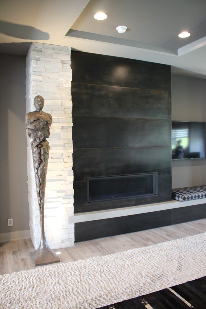 Imagen de salón abierto moderno sin televisor con paredes negras, chimenea lineal y marco de chimenea de piedra