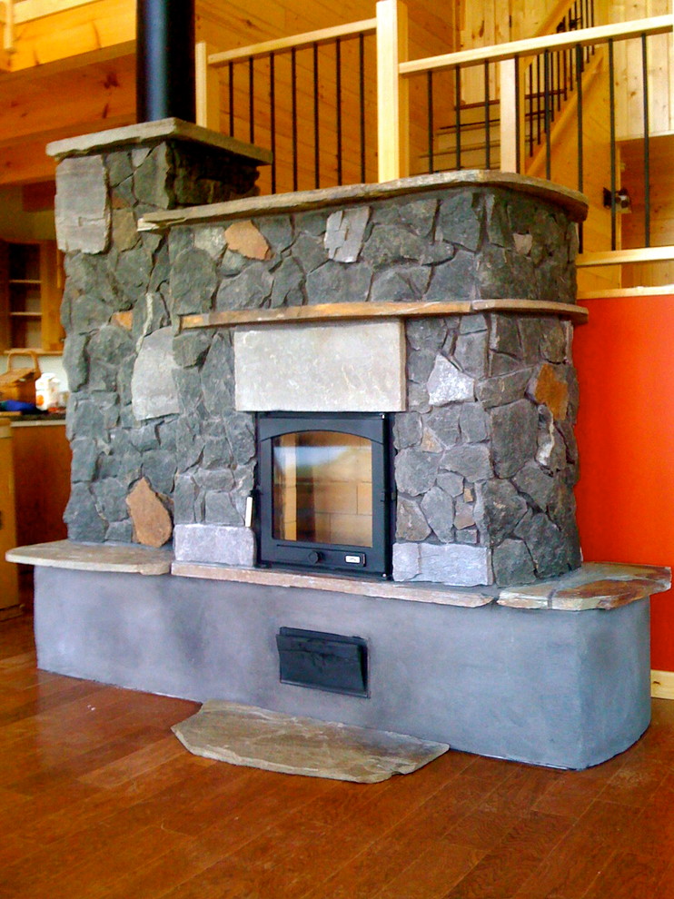 Aménagement d'un salon montagne avec un poêle à bois et un manteau de cheminée en pierre.
