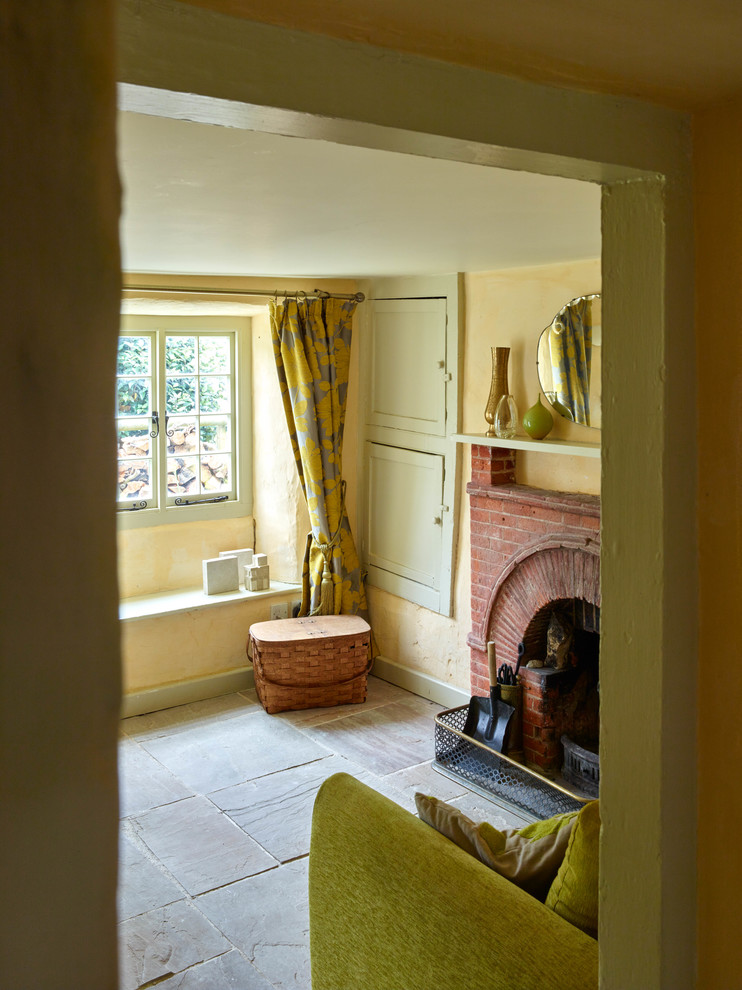 Trendy enclosed living room photo in London with yellow walls, a standard fireplace and a brick fireplace