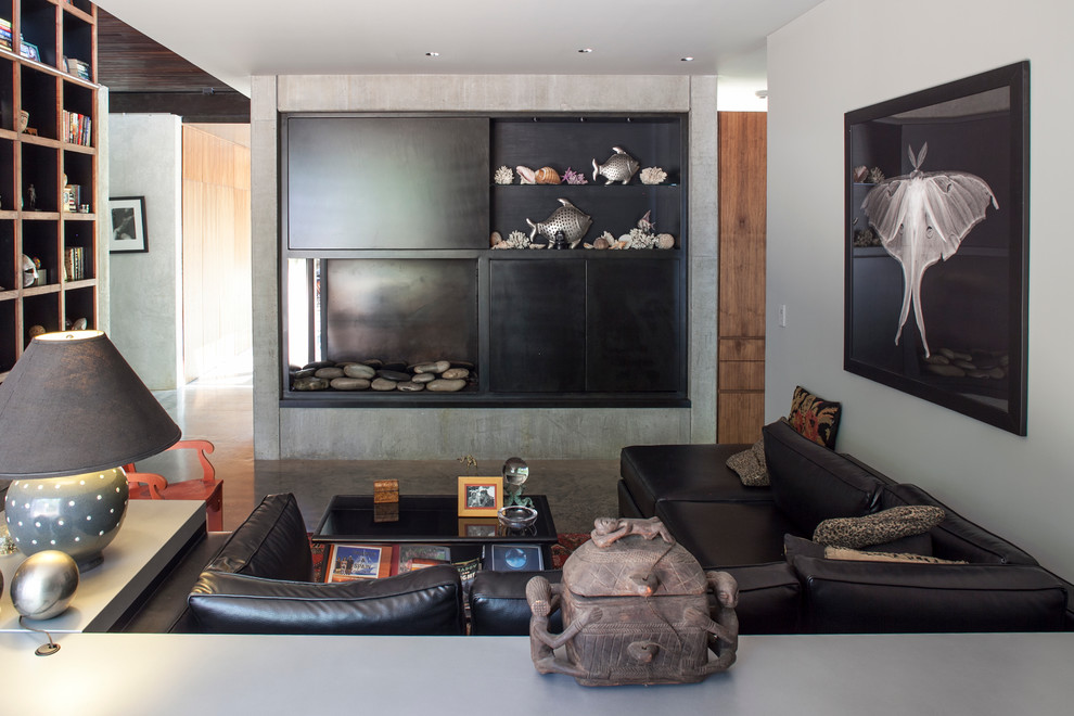 Réalisation d'un salon design avec un mur gris, une cheminée standard et canapé noir.