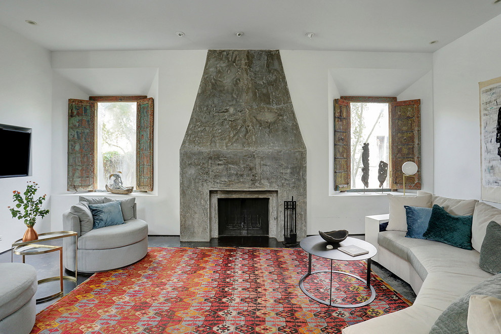 Inspiration pour un salon sud-ouest américain avec un mur blanc, sol en béton ciré, une cheminée standard et un manteau de cheminée en béton.