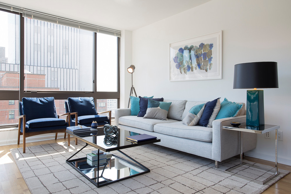 This is an example of a small modern grey and teal open plan living room in New York with white walls, light hardwood flooring, no fireplace and no tv.