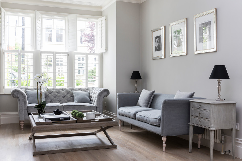 Example of a mid-sized transitional enclosed light wood floor and brown floor living room design in London with gray walls and no tv
