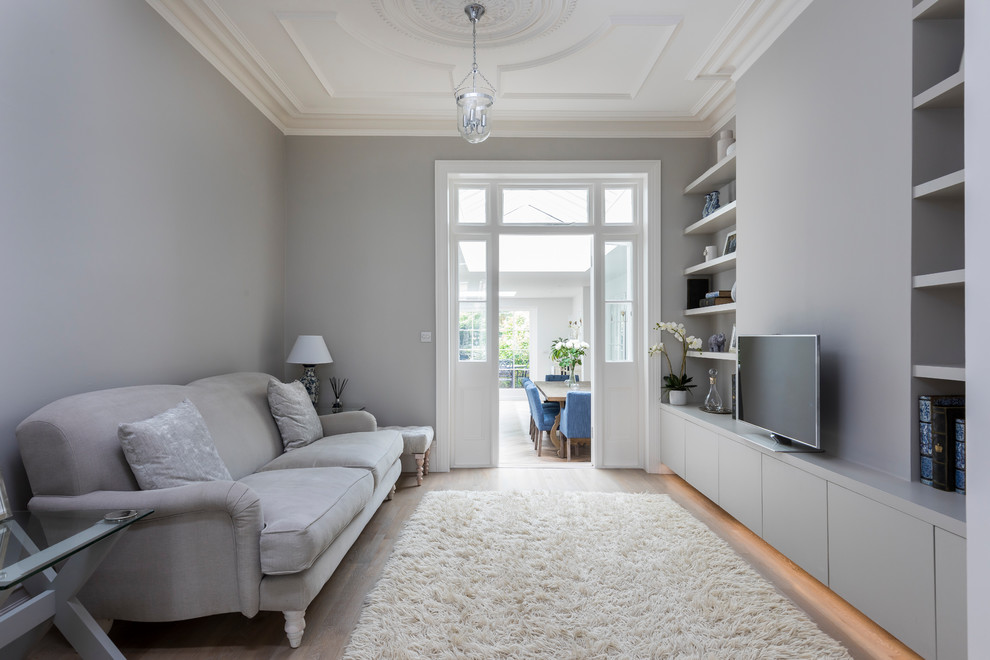 Идея дизайна: открытая гостиная комната среднего размера в стиле неоклассика (современная классика) с серыми стенами, светлым паркетным полом, отдельно стоящим телевизором и коричневым полом без камина
