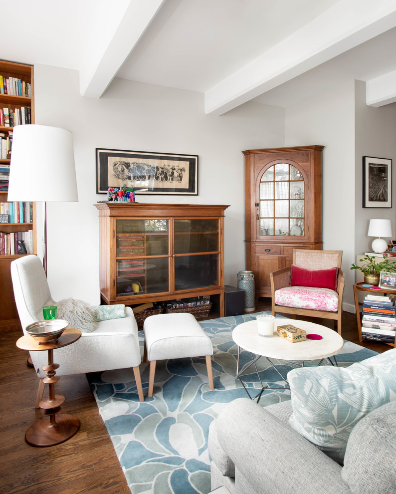 Immagine di un soggiorno classico di medie dimensioni con libreria, pareti bianche, pavimento in legno massello medio, nessun camino, TV nascosta e pavimento marrone