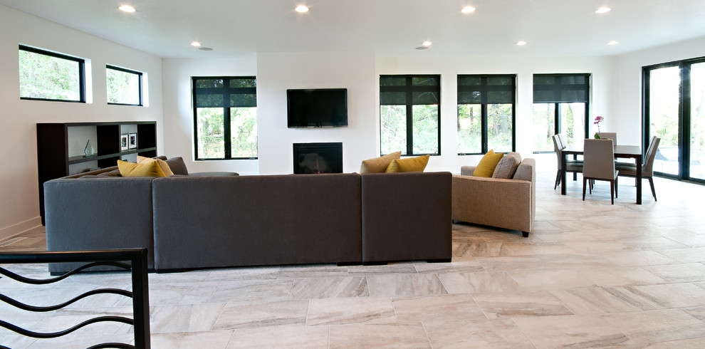 Стильный дизайн: открытая гостиная комната в стиле модернизм с белыми стенами, полом из керамогранита, стандартным камином и телевизором на стене - последний тренд