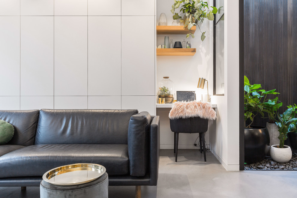 Esempio di un soggiorno contemporaneo di medie dimensioni e aperto con pareti grigie, pavimento in cemento, TV a parete e pavimento grigio