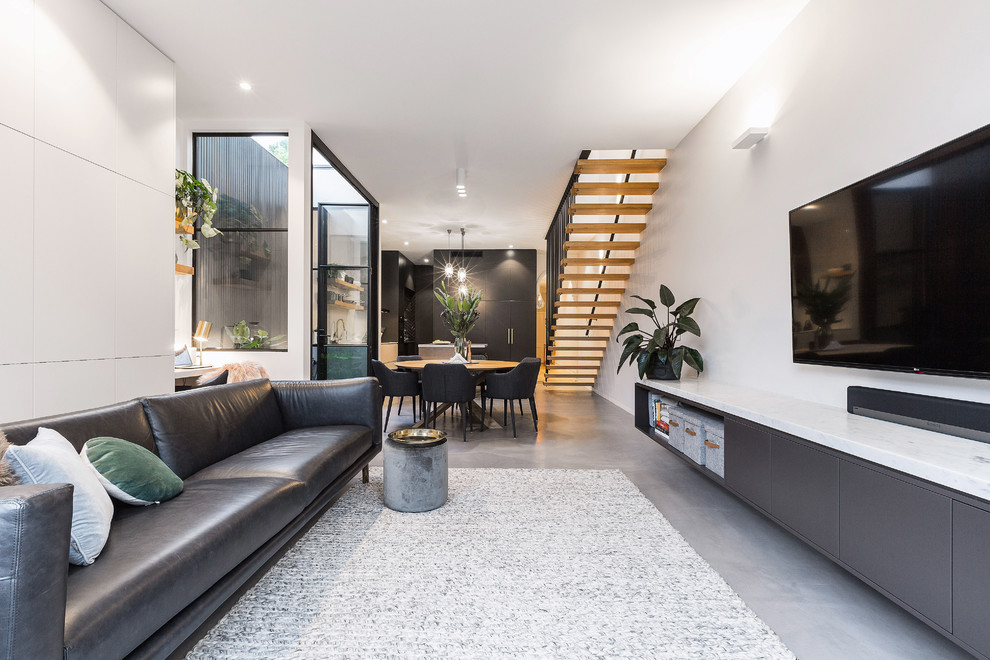 Ispirazione per un soggiorno minimal di medie dimensioni e aperto con pareti grigie, pavimento in cemento, TV a parete e pavimento grigio
