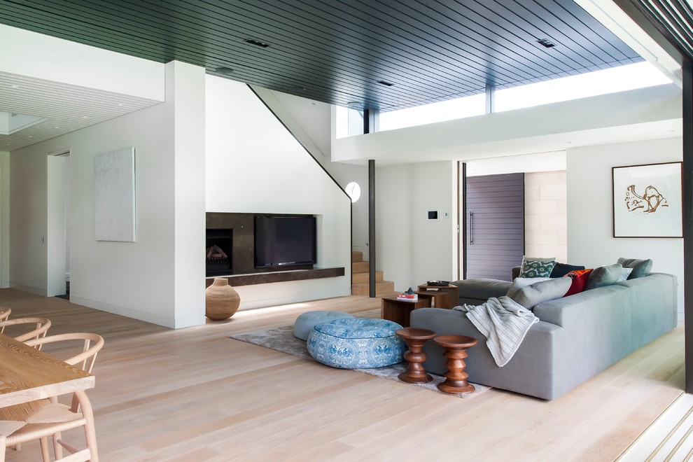 На фото: большая открытая гостиная комната в современном стиле с белыми стенами, паркетным полом среднего тона и отдельно стоящим телевизором