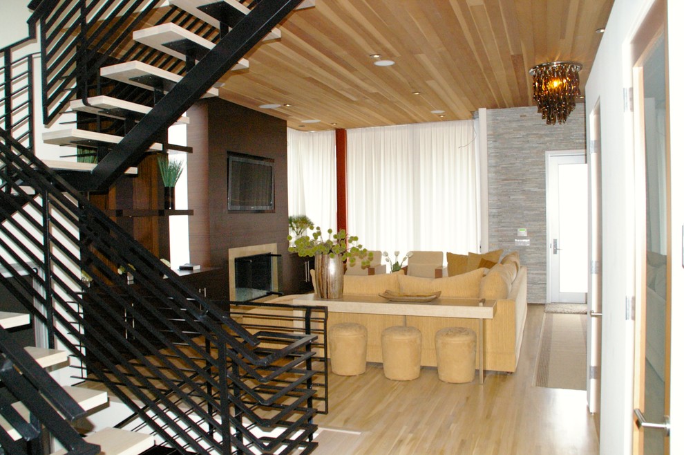 Foto de salón para visitas tipo loft moderno de tamaño medio con todas las chimeneas, marco de chimenea de piedra y pared multimedia