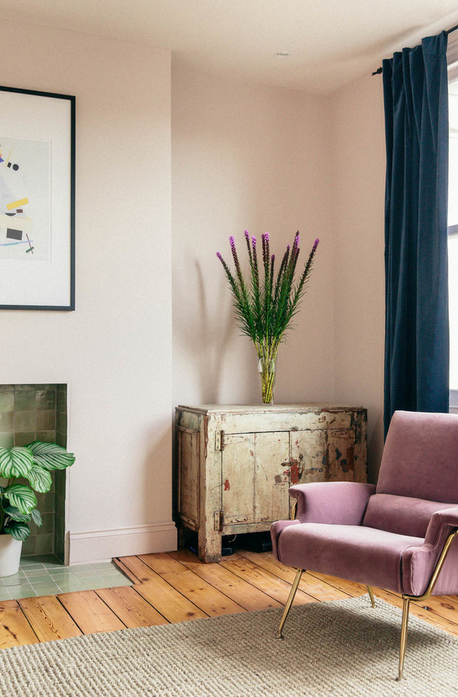 Danish medium tone wood floor living room photo in London with pink walls