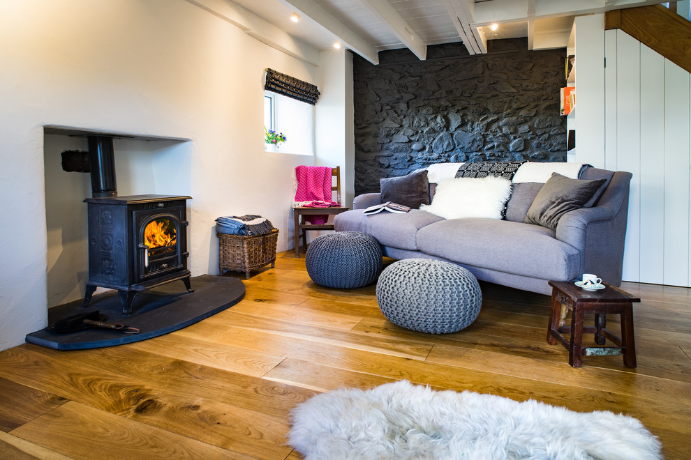 Kleines, Offenes Maritimes Wohnzimmer mit weißer Wandfarbe, hellem Holzboden, Kaminofen und braunem Boden in Sonstige